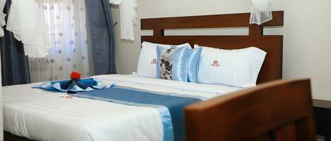 A neatly made bed with white and blue bedding, a wooden headboard, and a decorative blue and white pillow arrangement.