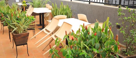 A rooftop terrace with outdoor seating, potted plants, and a view of the cityscape.