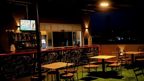 Un espace bar équipé d’un téléviseur, d’un comptoir et de tables et chaises pour que les clients puissent s’asseoir.