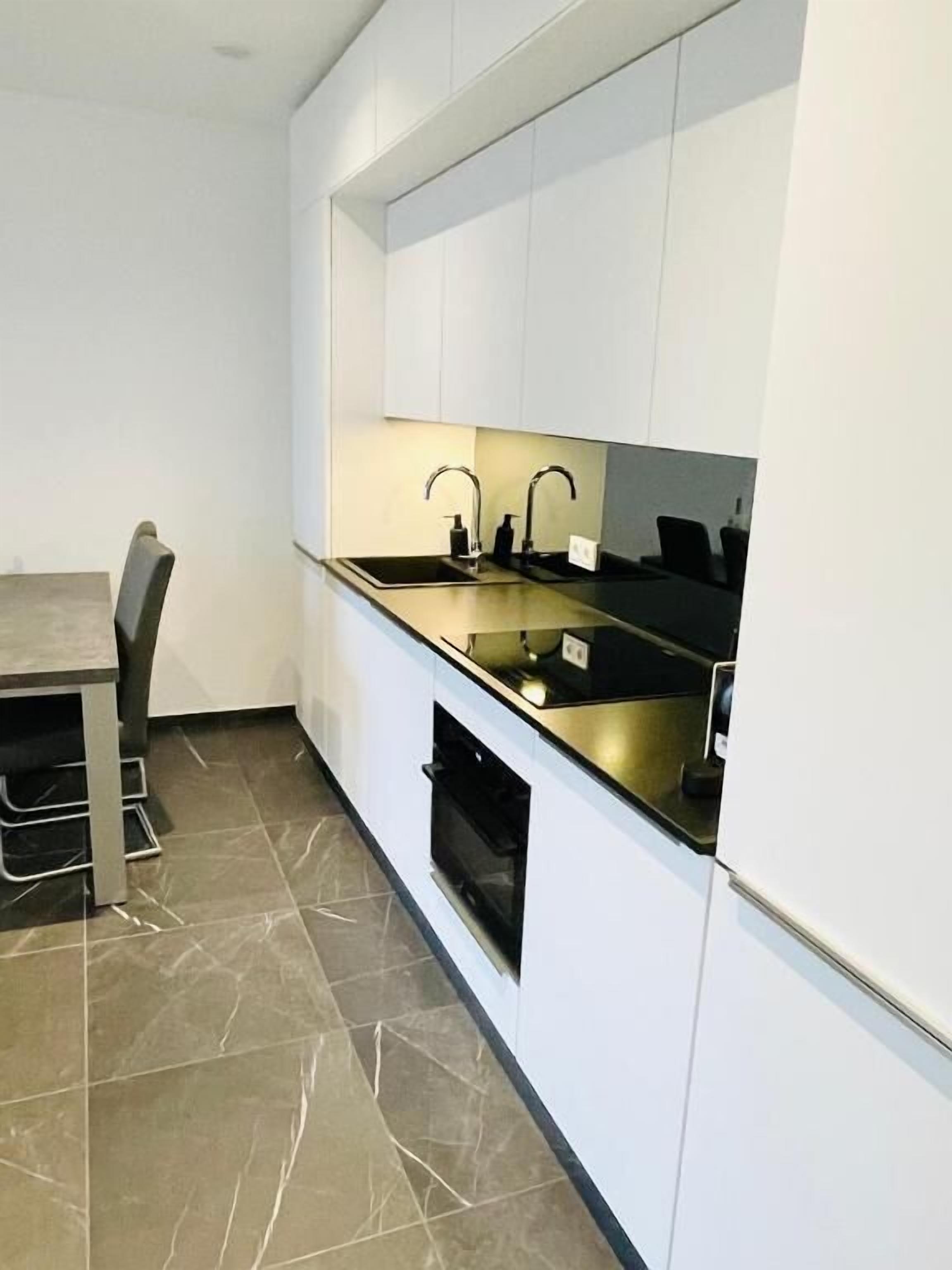 Een moderne keuken met witte kastjes, een zwart aanrecht en een inbouwoven.