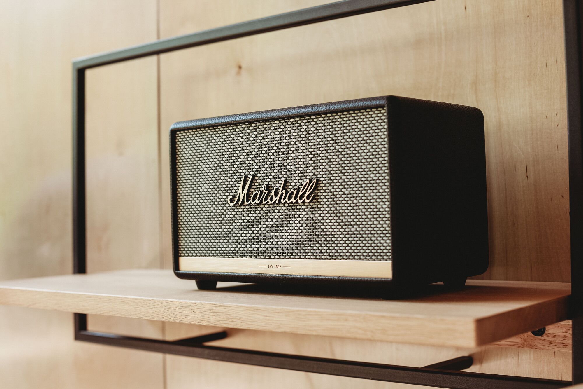 A vintage Marshall speaker on a wooden shelf against a wooden wall.