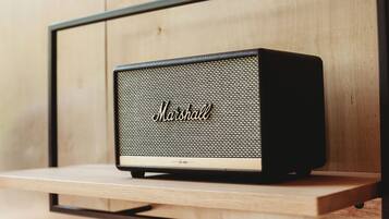 A vintage Marshall speaker on a wooden shelf against a wooden wall.