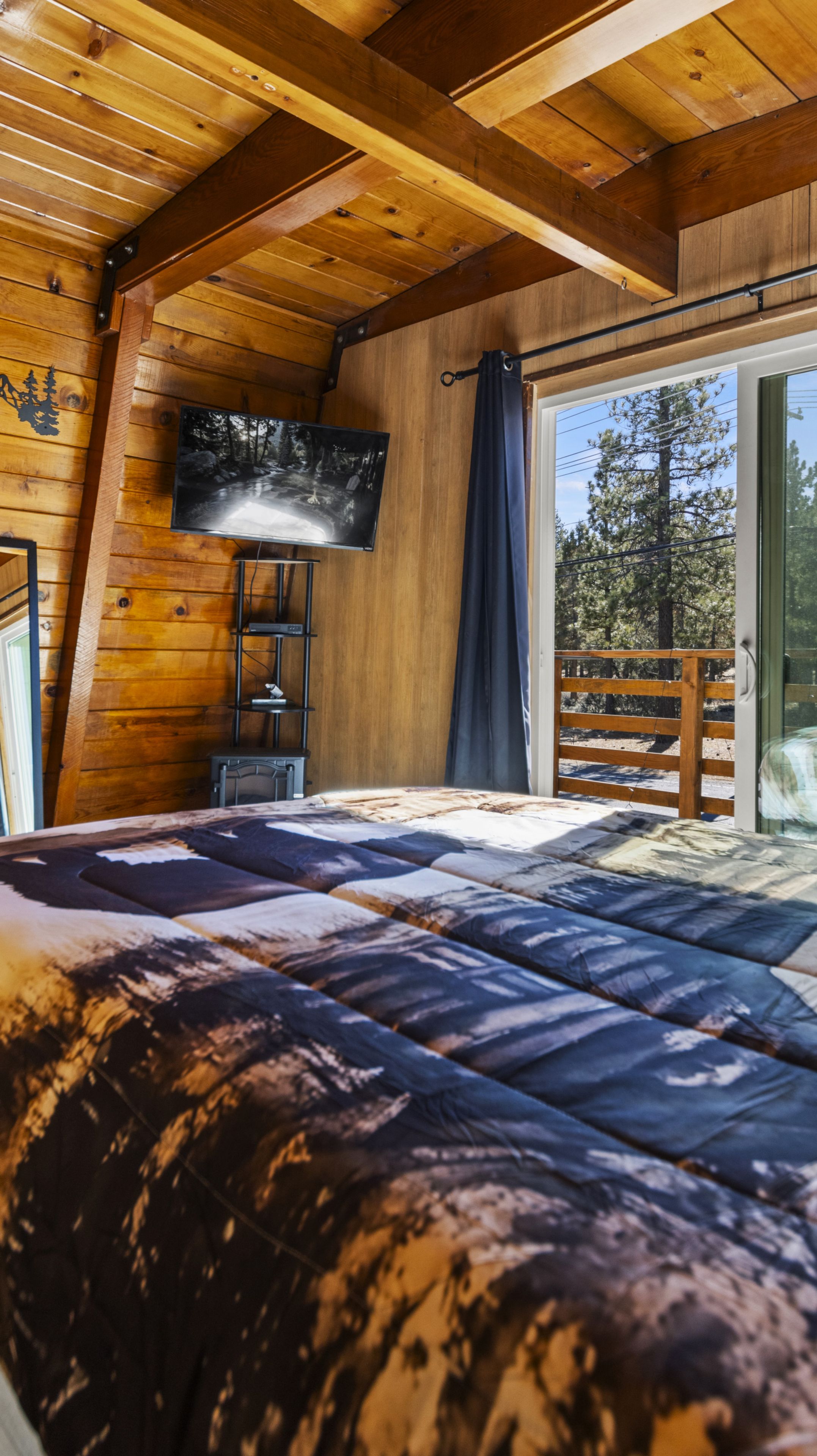 Quarto com uma cama, televisão e vista para o exterior.