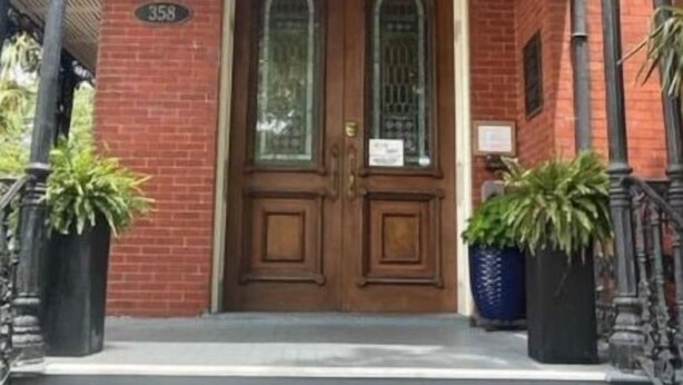 A brick building with a double door entrance, a number '358' above the door, and two potted plants on either side of the steps. - Historic private guest apartment (Norfolk)