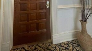 A wooden door with a grid pattern, a white wall with a light fixture, and a patterned rug. - Historic private guest apartment (Norfolk)