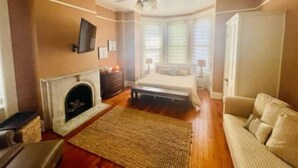 A bedroom with a fireplace, a bed, a sofa, and a ceiling fan. - Historic private guest apartment (Norfolk)