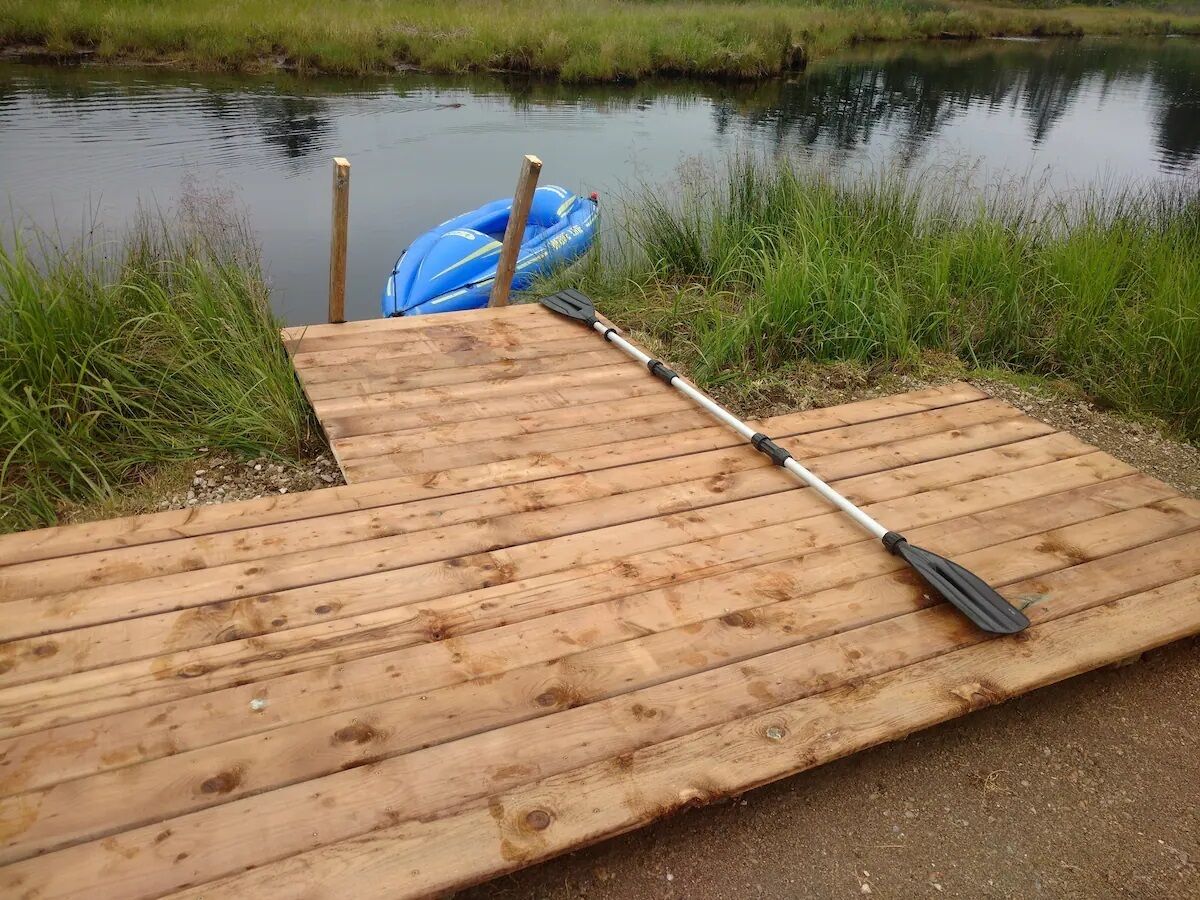 A wooden dock with a paddle and a blue kayak.
