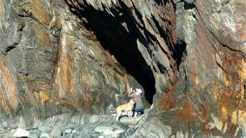 L’entrée d’une grotte rocheuse, avec un chien et une personne à l’intérieur.