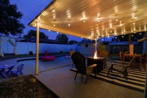 Relax in a serene outdoor space with a covered seating area, fire feature, and pool views.