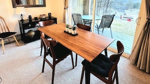 Un comedor con una mesa y sillas de madera, un espejo y vistas a través de un ventanal.