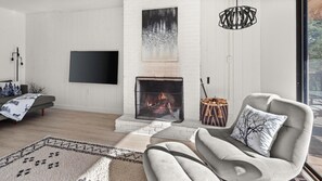 A modern living room with a fireplace, a sofa, a TV, and a patterned rug.