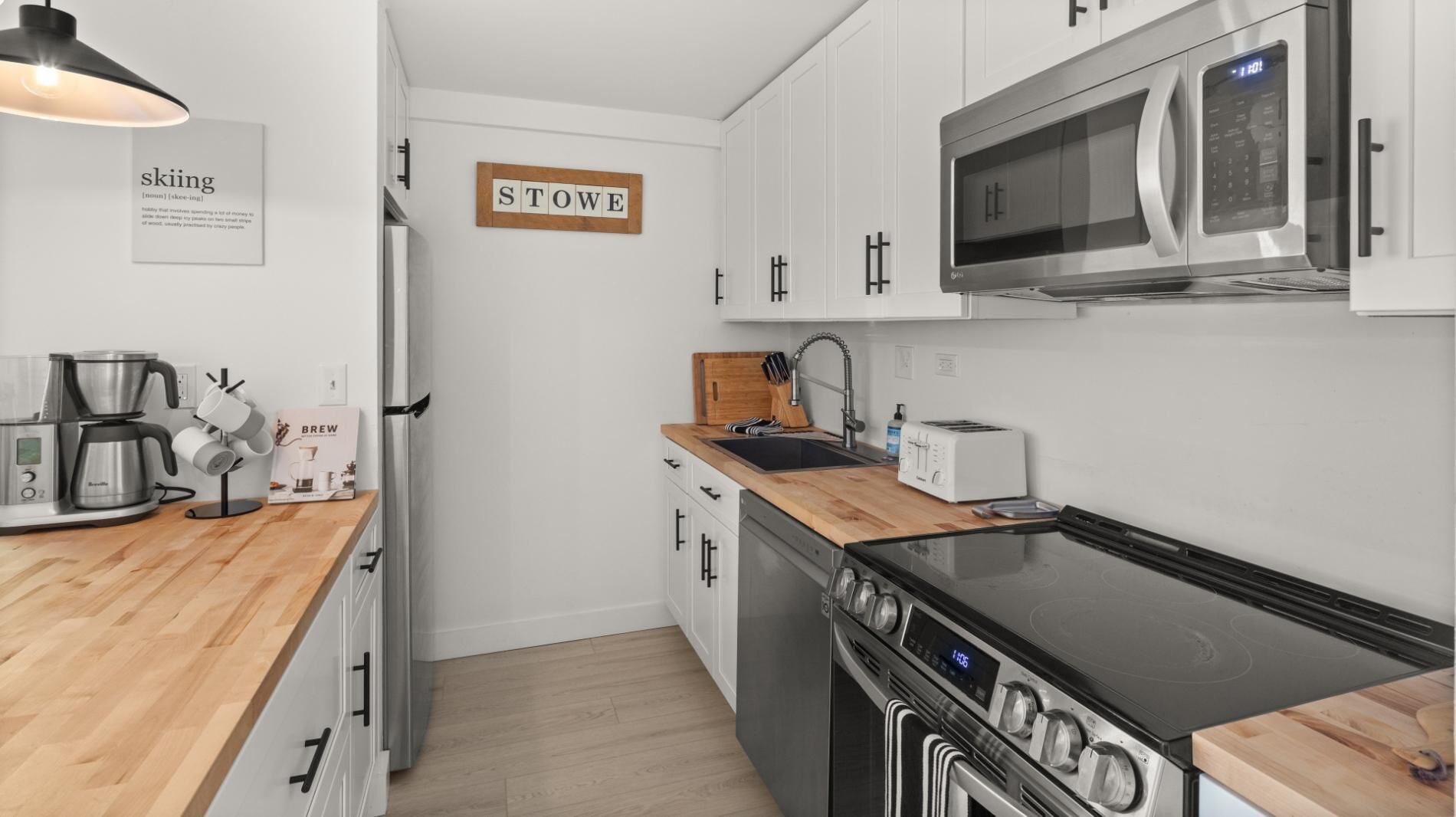 A modern kitchen with white cabinets, a microwave, a stove, a coffee maker, and a toaster.
