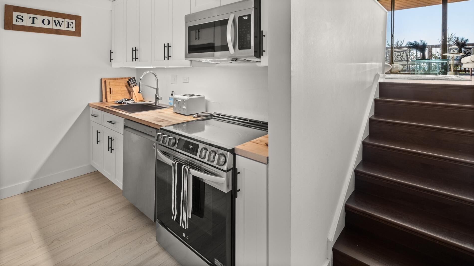 Une cuisine moderne avec des meubles blancs, un four à micro-ondes, un grille-pain et un four traditionnel.
