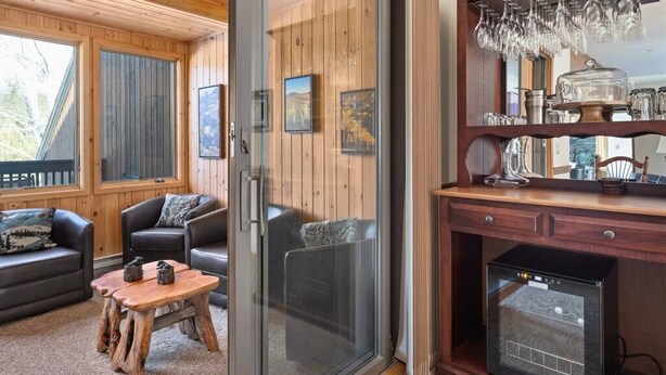 A cozy living room with a fireplace, wooden walls, and a glass door leading to a balcony. - Peaceful townhome in sought-after Stowe location (Stowe)