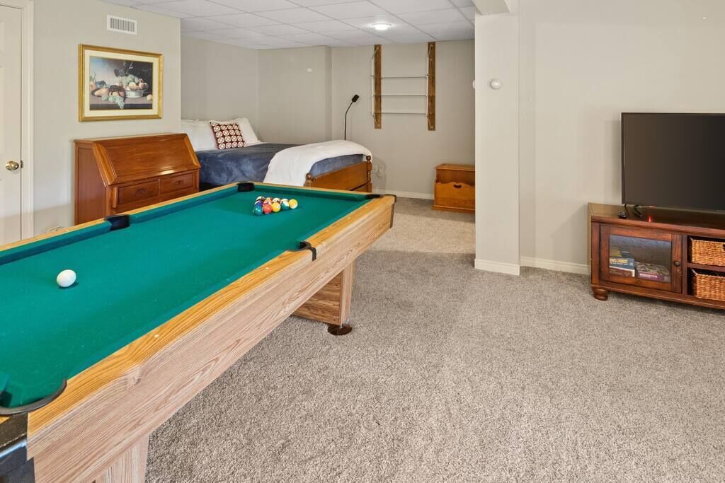 Une pièce équipée d’une table de billard, d’un lit, d’une télévision et d’une bibliothèque.