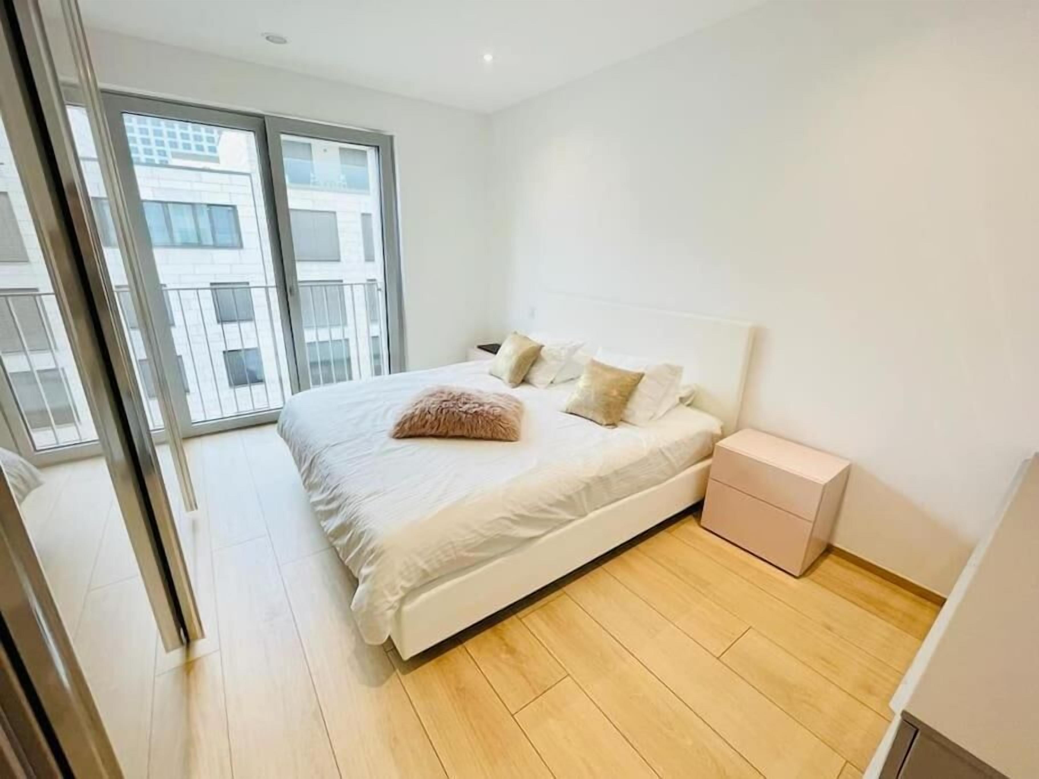 Ein Schlafzimmer mit einem großen Bett, einem Nachttisch und einer Schiebetür, die auf einen Balkon führt.