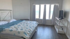 A bedroom with a bed, a TV on a stand, and a window with curtains.