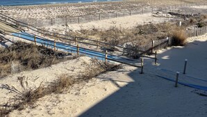 A sandy beach with a blue pathway and wooden fences.