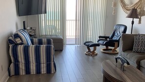 A living room with a striped sofa, a round wooden coffee table, a leather armchair, and a grey sofa.