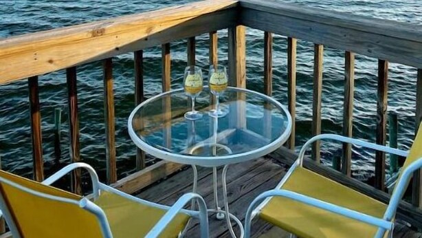 A deck with a glass table and yellow chairs, overlooking a body of water. - Waterfront! Private, Sunrises & Sunsets, Sea life, Deck, 10 minutes to Destin! (Niceville)