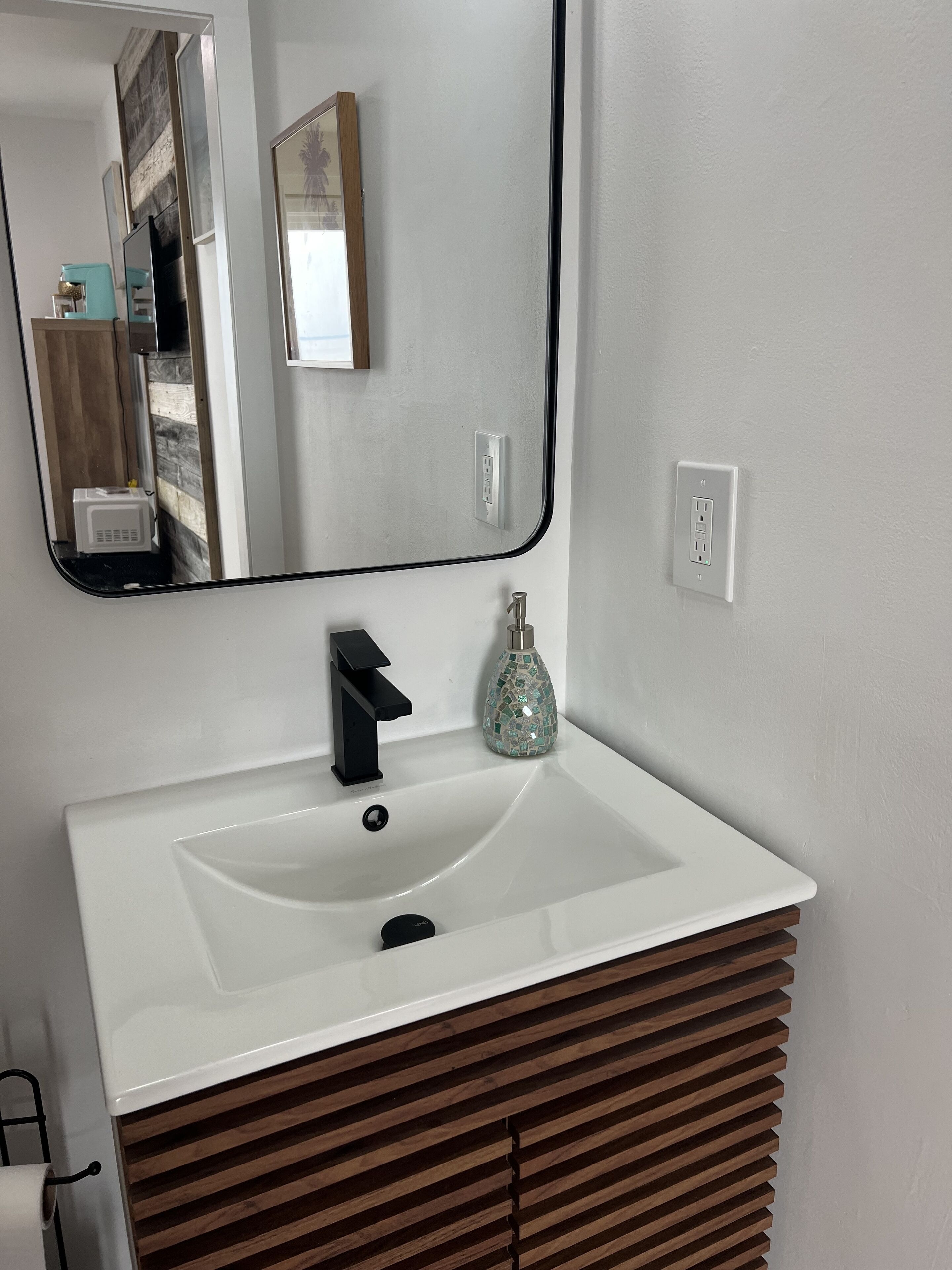 A bathroom with a white sink, black faucet, and a mirror above it.