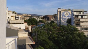 A cityscape with a prominent building featuring a large emblem on its facade. - AgiouOrous10  ·  Acropolis view top floor apartmen (Athens)