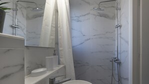 A modern bathroom with a marble-tiled shower, a white sink, and a towel rack. - AgiouOrous10  ·  Acropolis view top floor apartmen (Athens)