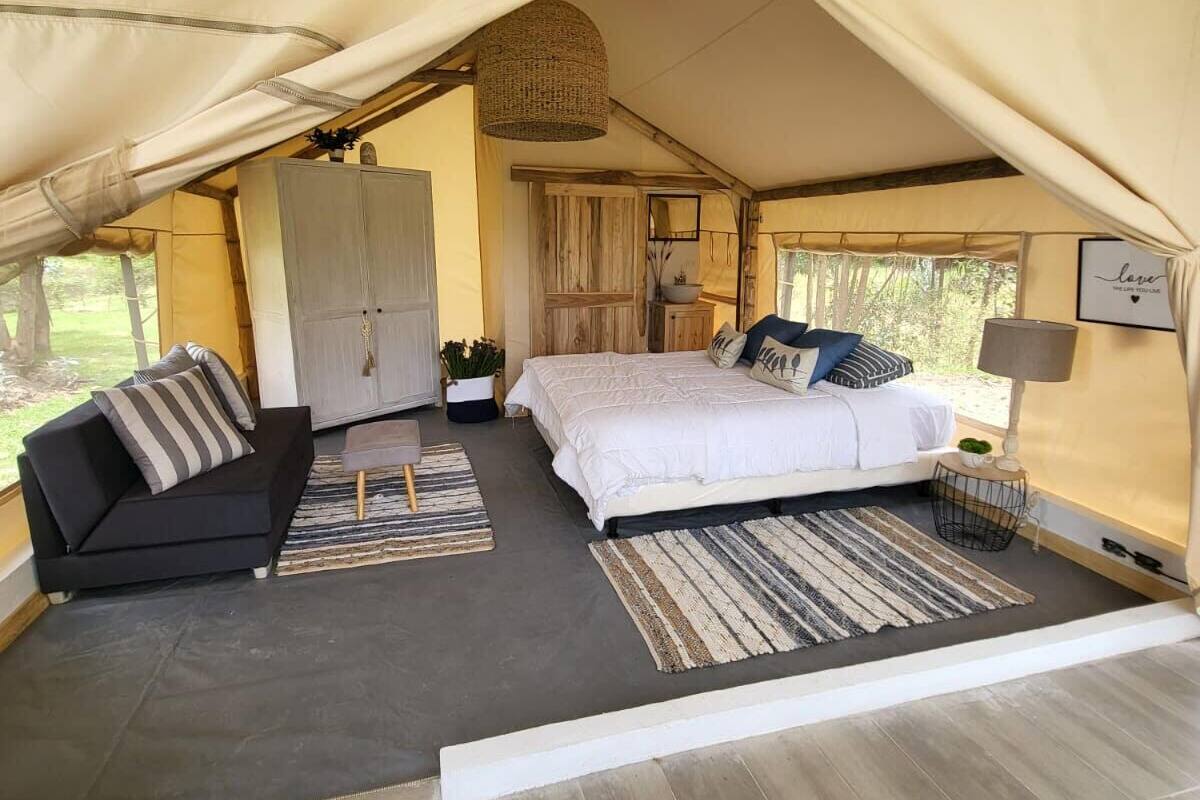 Acomodação em tenda com cama, sofá e guarda-roupa.