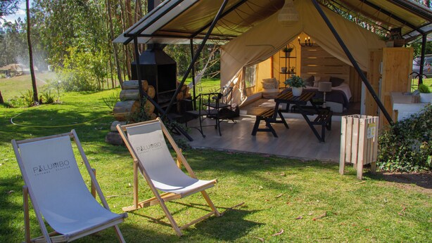 A cozy outdoor seating area with a tent structure, a barbecue grill, and two lounge chairs labeled "Pålumbo." - Palumbo Glamping & Villas (Cangahua)