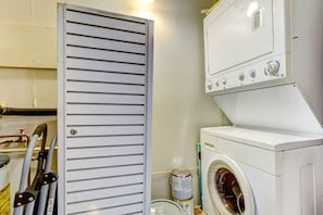 Convenient laundry facilities with a front-loading washing machine and stacked dryers.