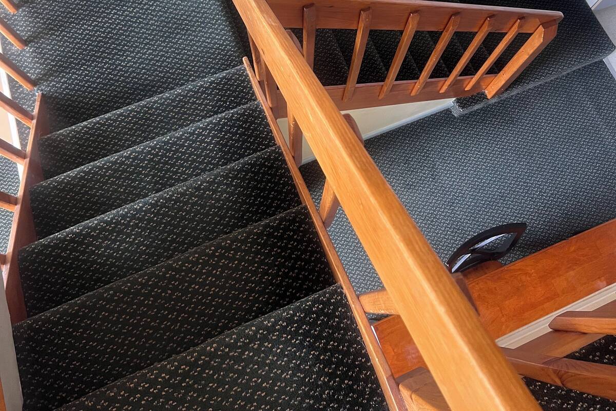 Eine Treppe mit Holzgeländer und Teppichstufen.