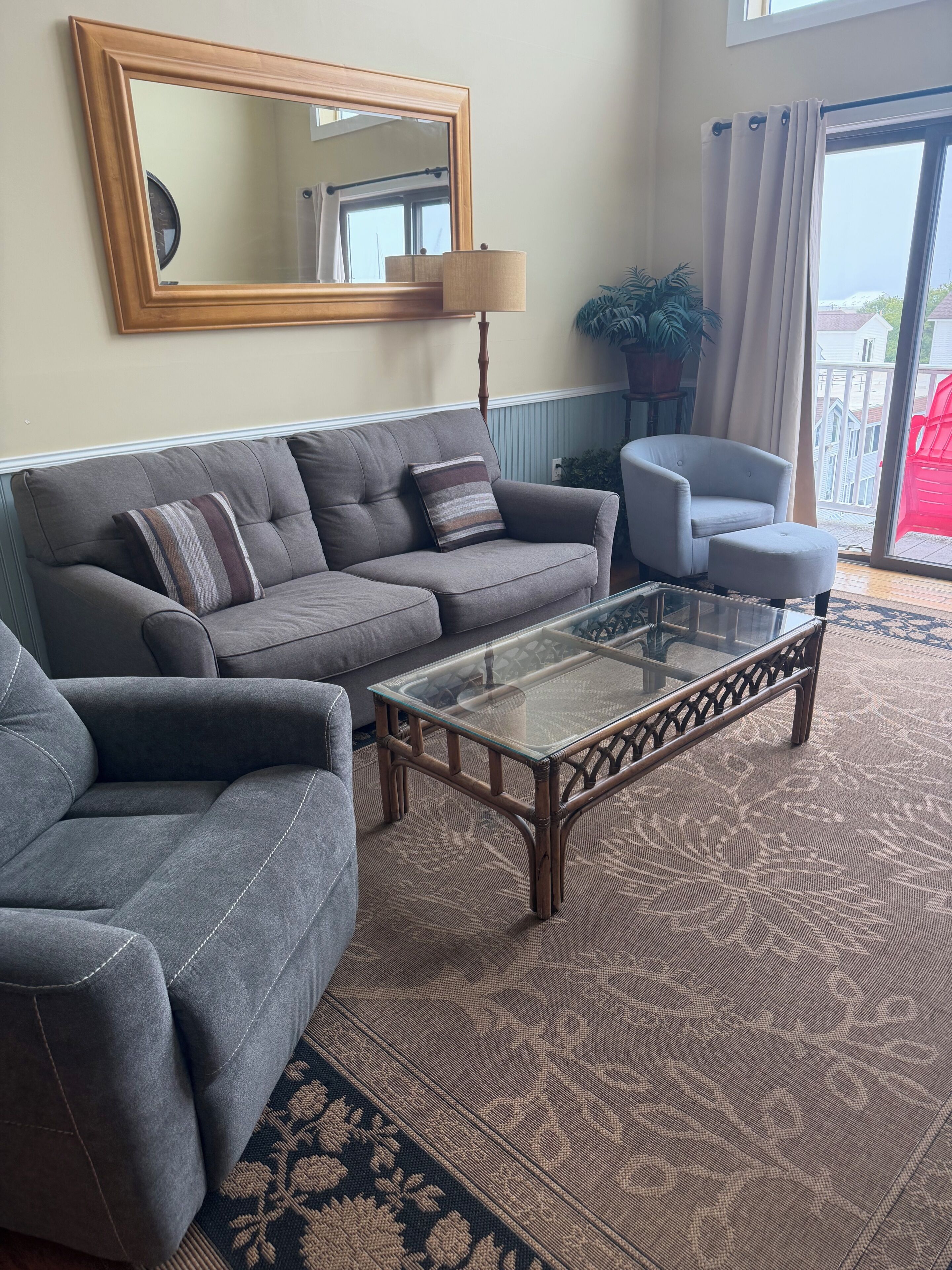 A living room with a sofa, armchair, and glass coffee table.