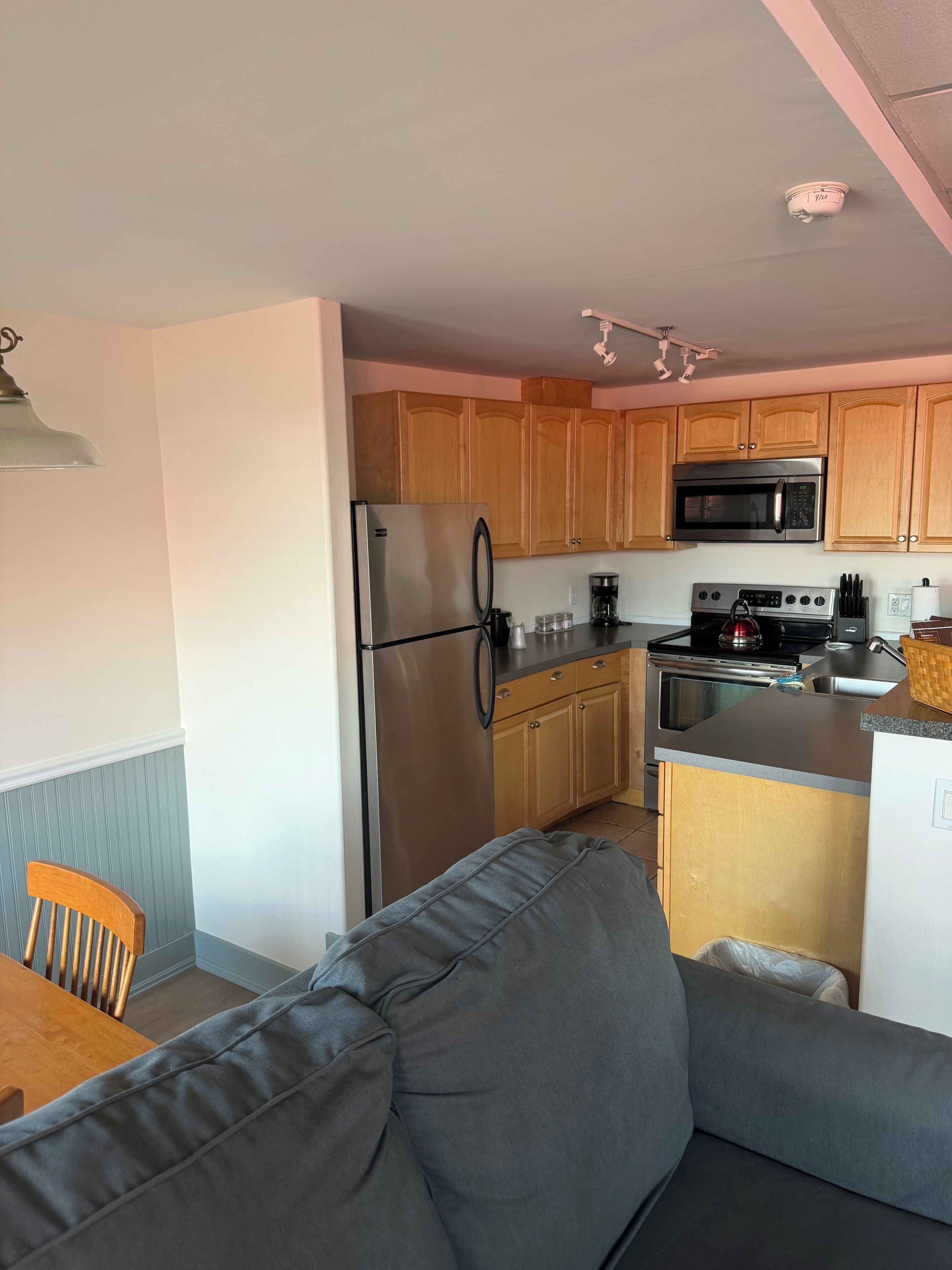 A compact kitchen with wooden cabinets, a stainless steel refrigerator, a microwave, and a stove.