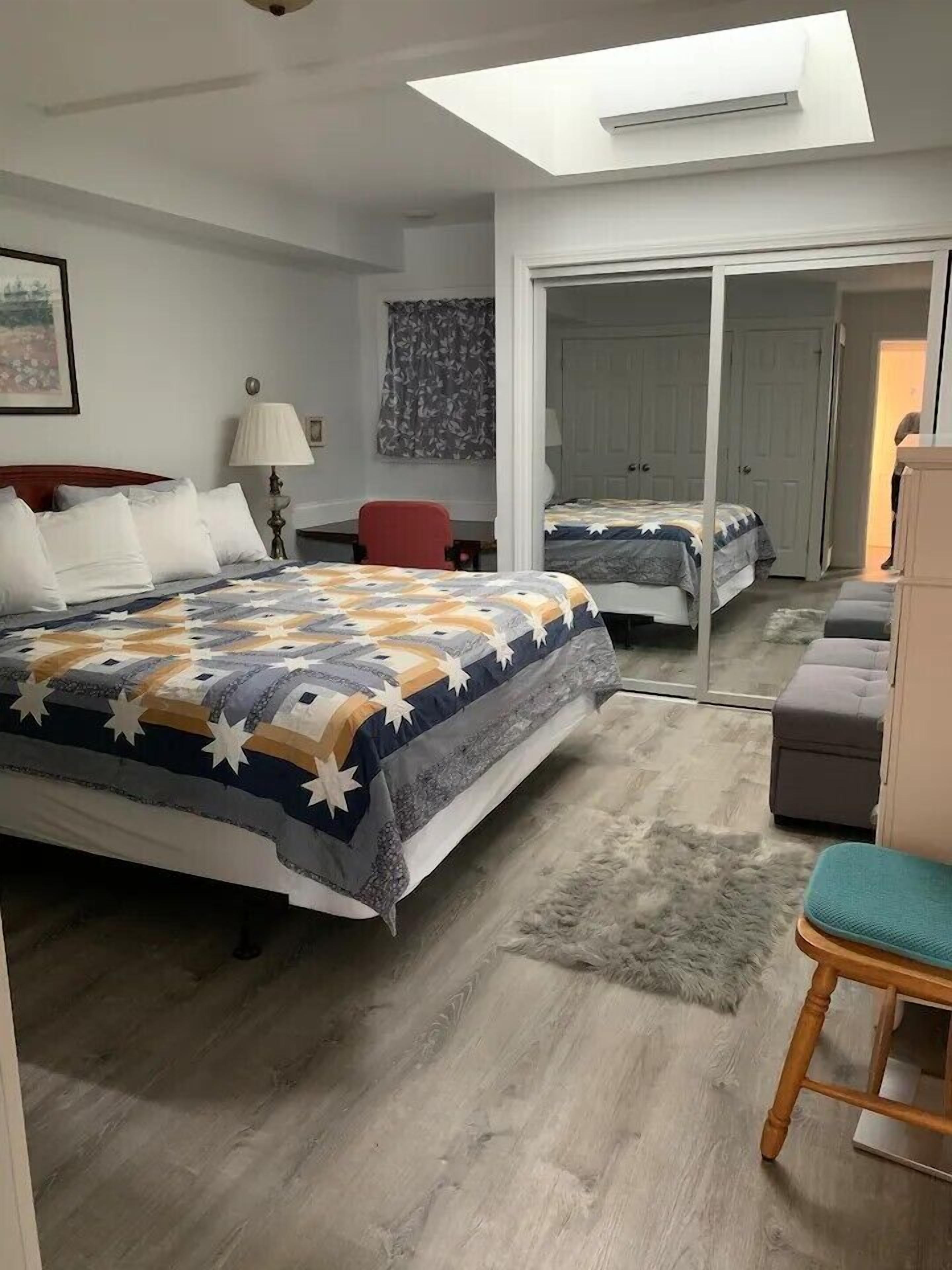 A bedroom with a large bed, a desk, a chair, and a wardrobe.