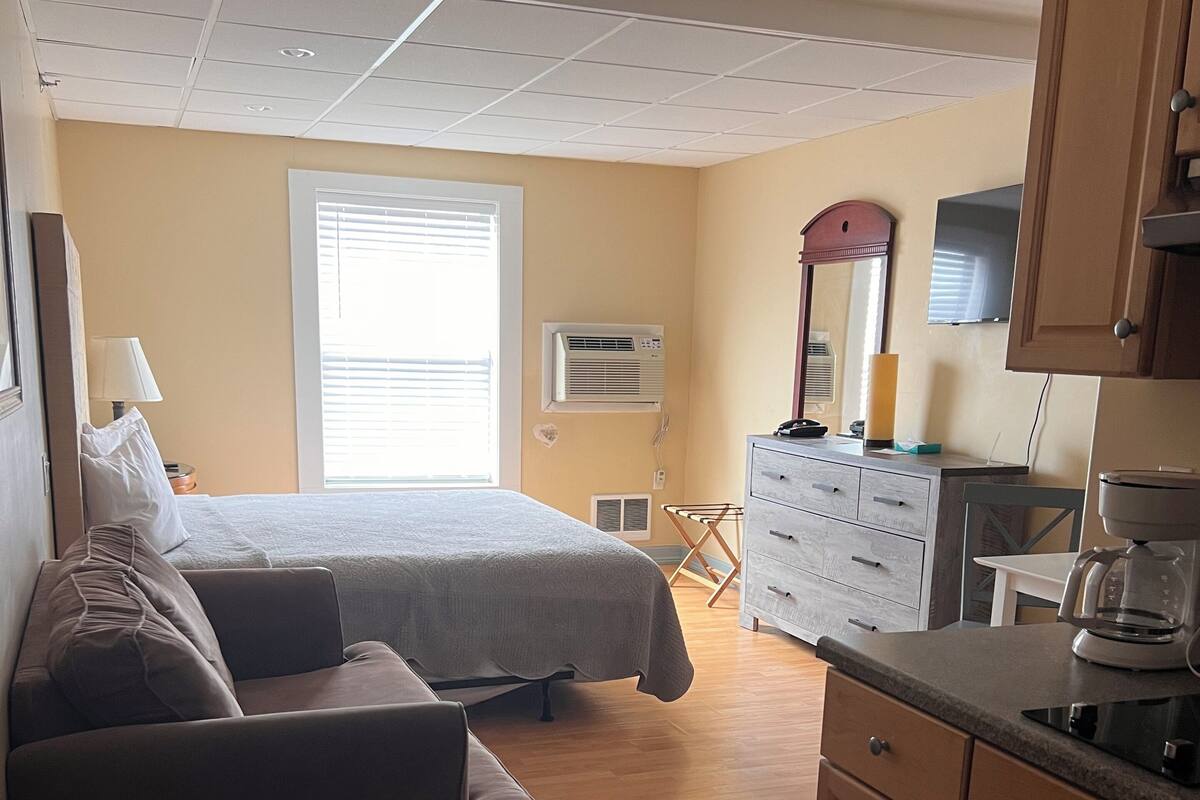 Ein Schlafzimmer mit Bett, einer Couch, einem Schminktisch und einer Küchenzeile.