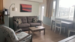 A living room with a sofa, armchair, coffee table, and a painting on the wall. - Trade Winds on the Bay (Rockland)