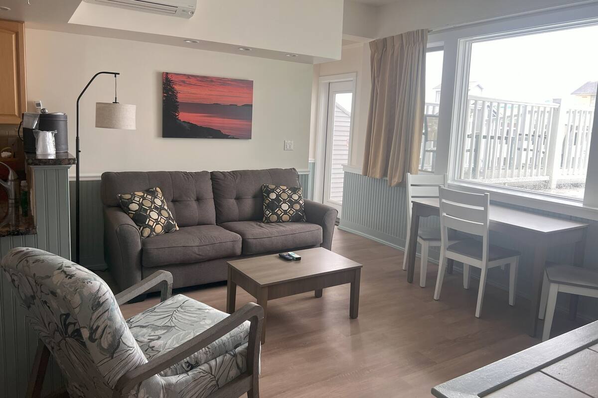 Ein Wohnzimmer mit Sofa, Sessel, Couchtisch und einem Gemälde an der Wand.