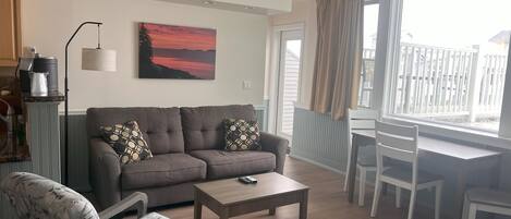A living room with a sofa, armchair, coffee table, and a painting on the wall.