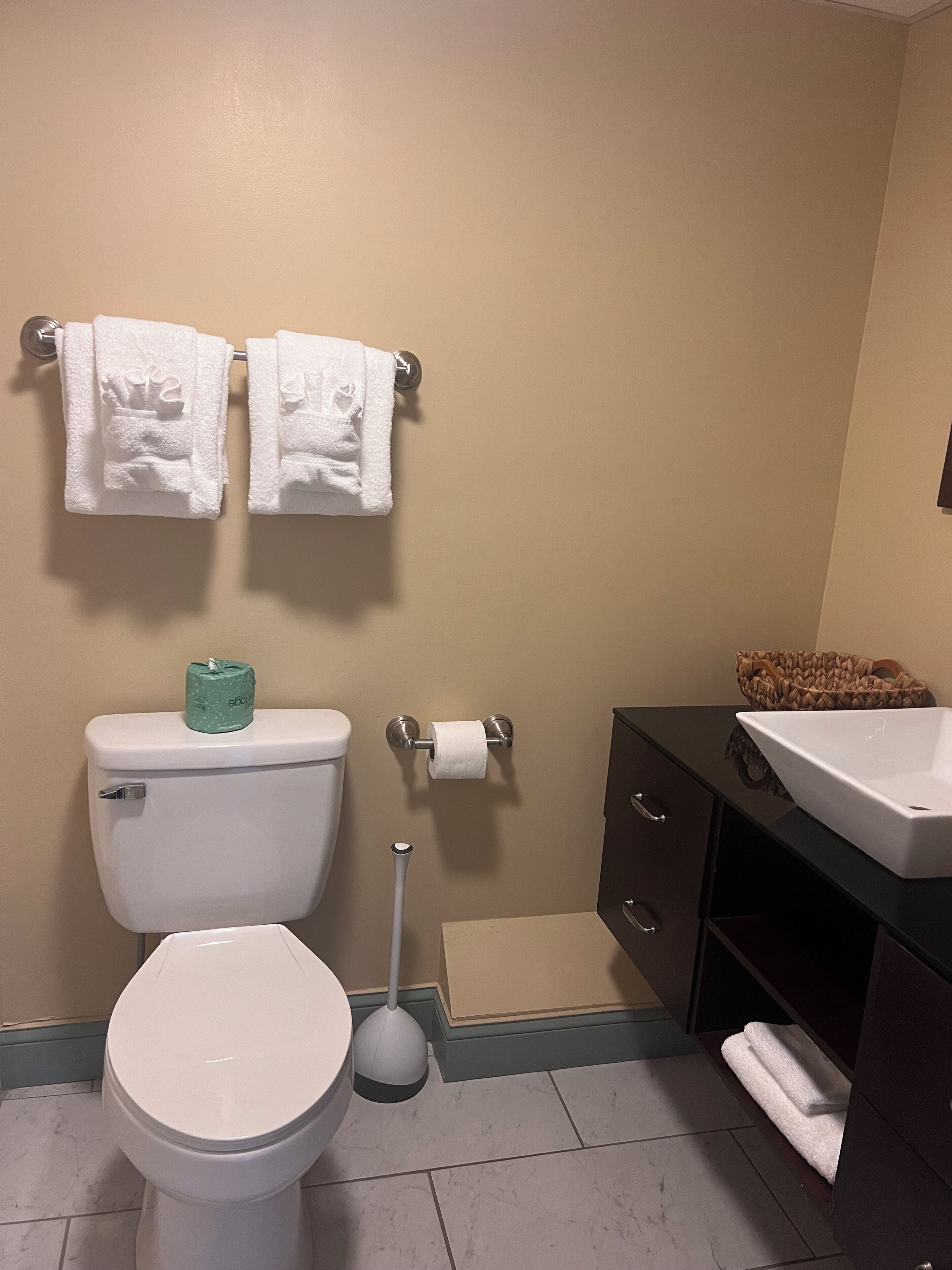 Un bagno con il water, un bidet, un lavandino e un porta asciugamani con due asciugamani.