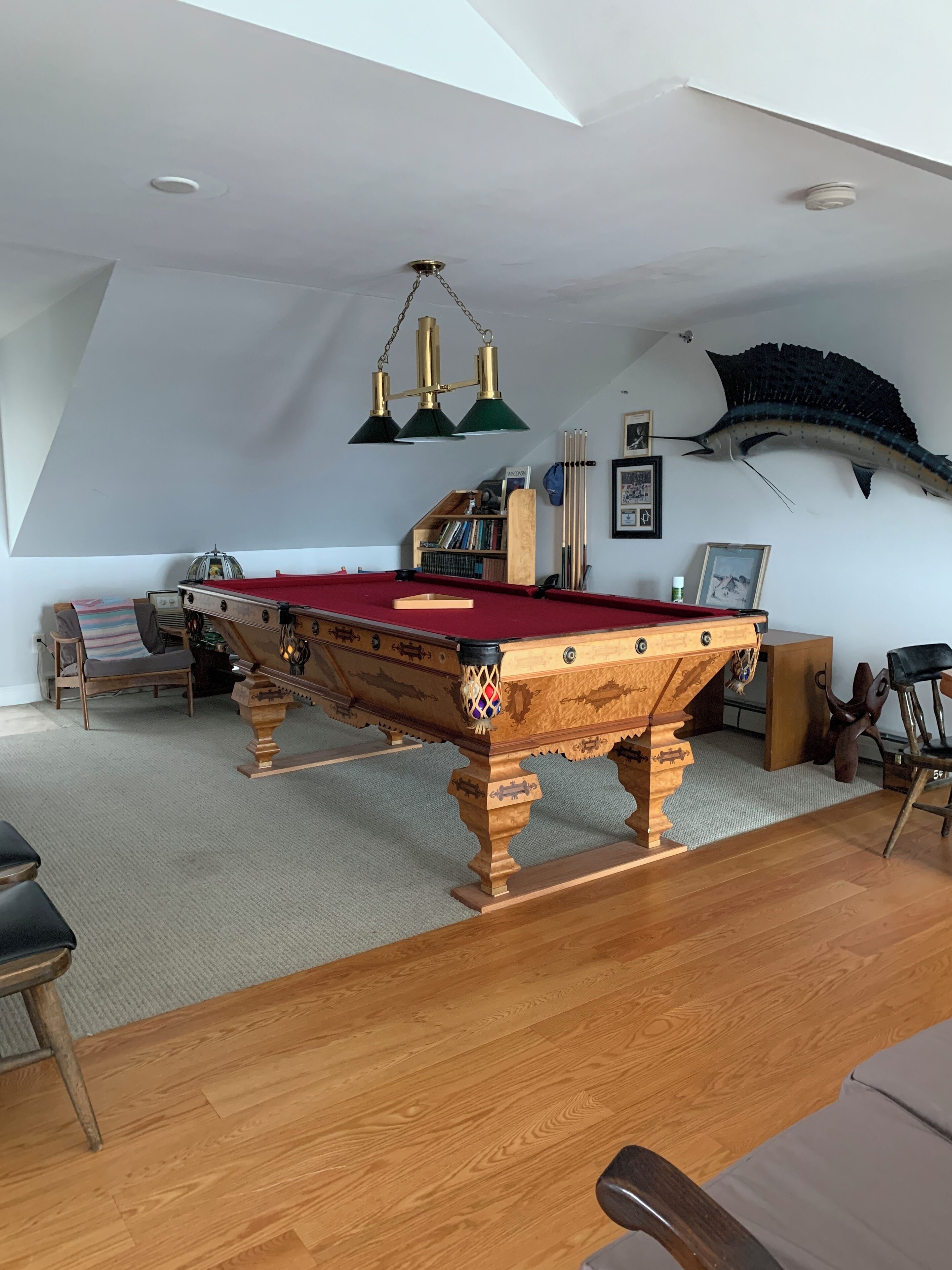 Ein geräumiger Raum mit Billardtisch, Holzmöbeln und einer Decke mit Dachfenster.