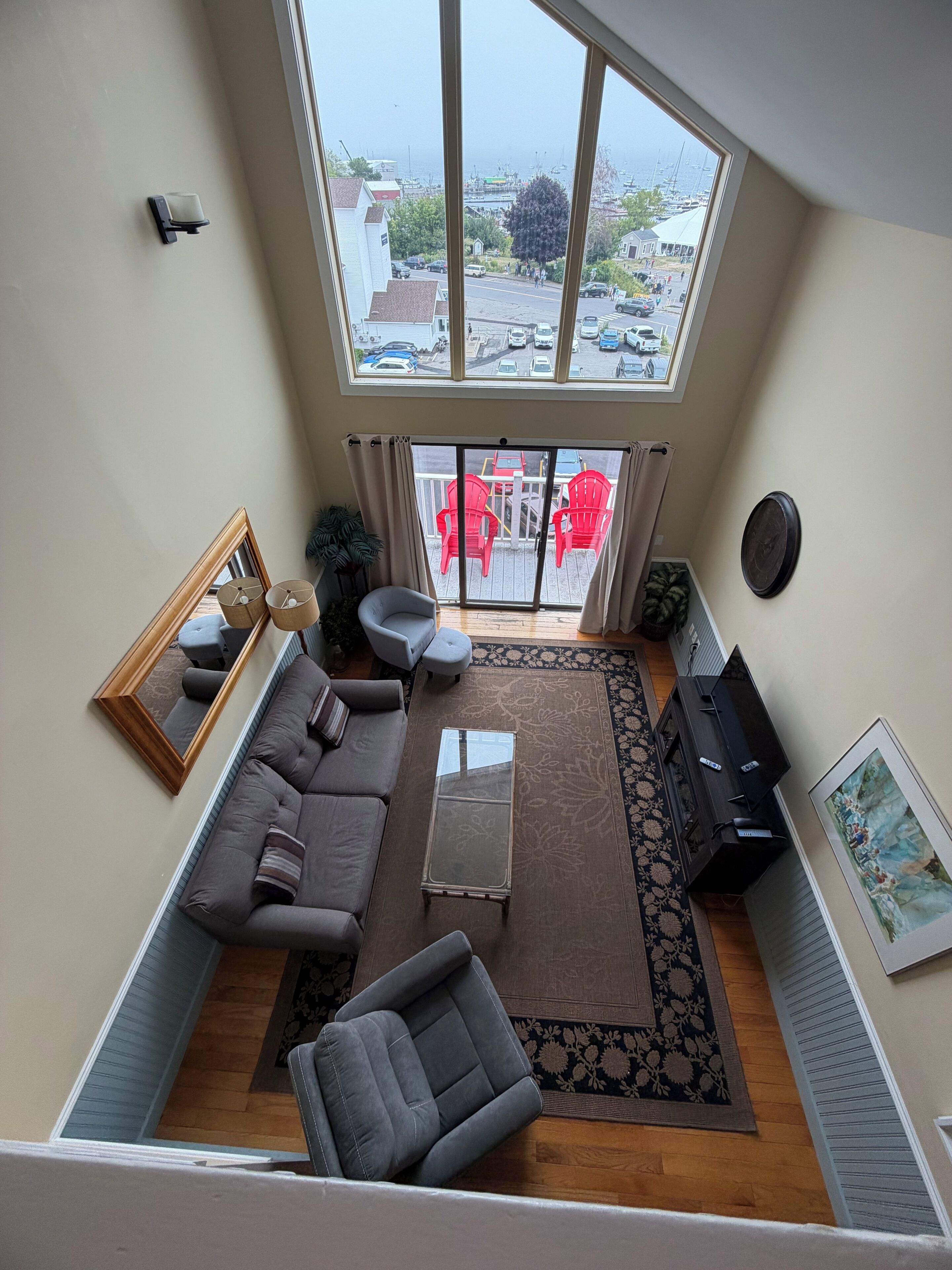 A spacious living area with a large window, a sofa set, a coffee table, and a TV.