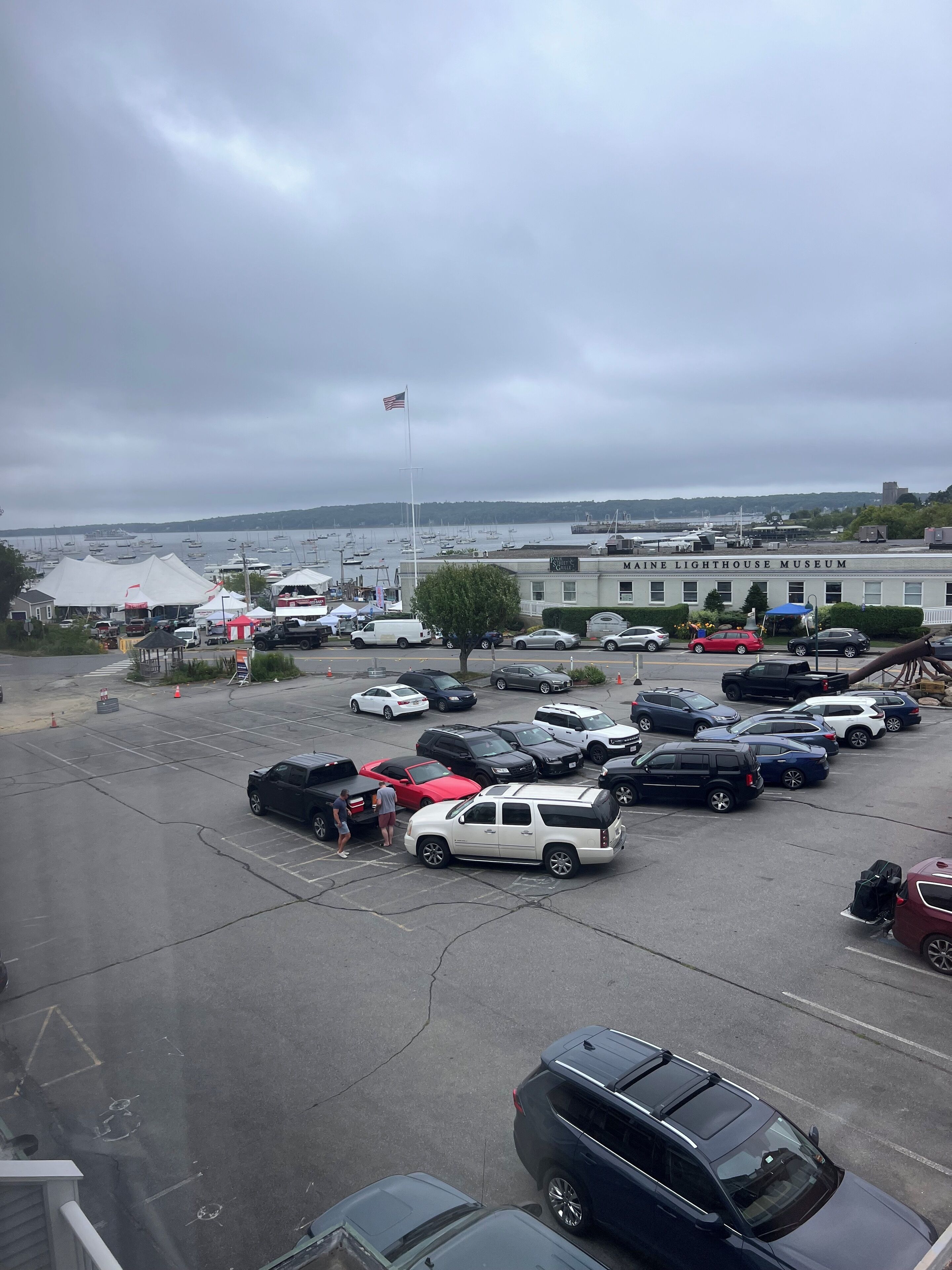 Un parking où sont garées différentes voitures, et en arrière-plan, un bâtiment sur lequel on peut lire l’inscription « MUSÉE DES PHARES DU MAINE ».