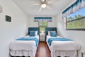 A bedroom with two beds, a ceiling fan, a window with blinds, and a wall-mounted light fixture. - Scenic Waterfront Getaway – Private Stay (Oldsmar)