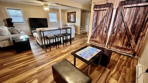 Un salon avec un plancher en bois, un canapé, une table basse et un téléviseur.