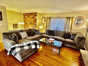 A living room with two sofas, a coffee table, and a brick accent wall.