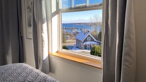 Un dormitorio con un amplio ventanal con vistas a un puerto y una casa.