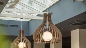 Un restaurante con techos altos, iluminación colgante moderna y vistas del cielo a través de tragaluces. Las mesas están dispuestas con manteles blancos y sillas.
