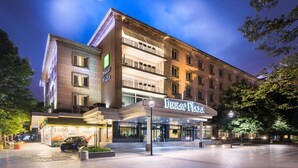 Un hotel con fachada moderna, varios balcones y una entrada bien iluminada.