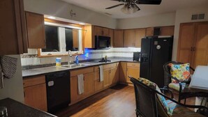A kitchen with wooden cabinets, a microwave, a refrigerator, a dishwasher, and a ceiling fan.