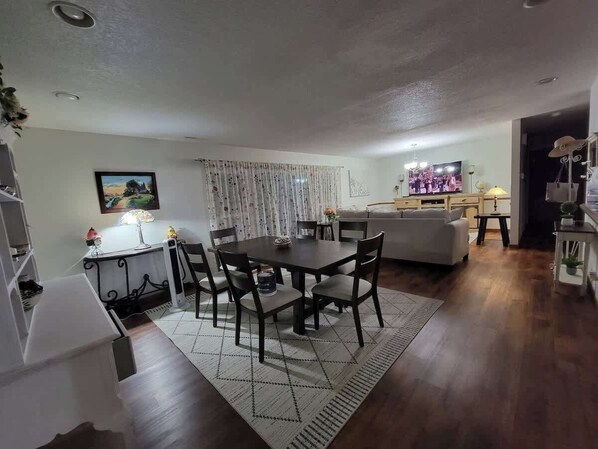 A dining area with a table and chairs, a sofa, a television, and a staircase.